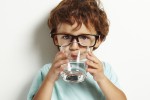 Portrait of boy drinking glass of water isolated in white
