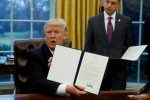 U.S. President Donald Trump holds up the executive order on withdrawal from the Trans Pacific Partnership after signing it as White House Chief of Staff Reince Priebus stands at his side in the Oval Office of the White House in Washington January 23, 2017.   REUTERS/Kevin Lamarque