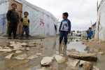 A Syrian refugee boy stands in a pool of water as he looks at others outside tents at a makeshift settlement in Bar Elias in the Bekaa valley January 5, 2015. Lebanon enforced new immigration controls at the Syrian border on Monday in a move to gain control of the steady stream of refugees from its much larger neighbour. REUTERS/Mohamed Azakir (LEBANON - Tags: SOCIETY IMMIGRATION CIVIL UNREST CONFLICT POLITICS)