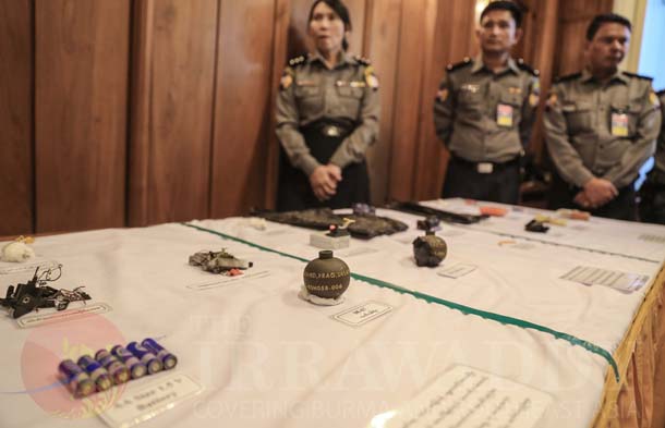 Police officers stand beside a table of explosive devices which were discovered over the past week in five divisions and states, at a press conference on Friday at the Rangoon Division government office. (Photo: JPaing / The Irrawaddy)