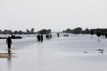 FILE PHOTO: People walk amid rising flood waters on the Indus highway, following rains and floods during the monsoon season in Mehar, Pakistan August 31, 2022. REUTERS/Akhtar Soomro